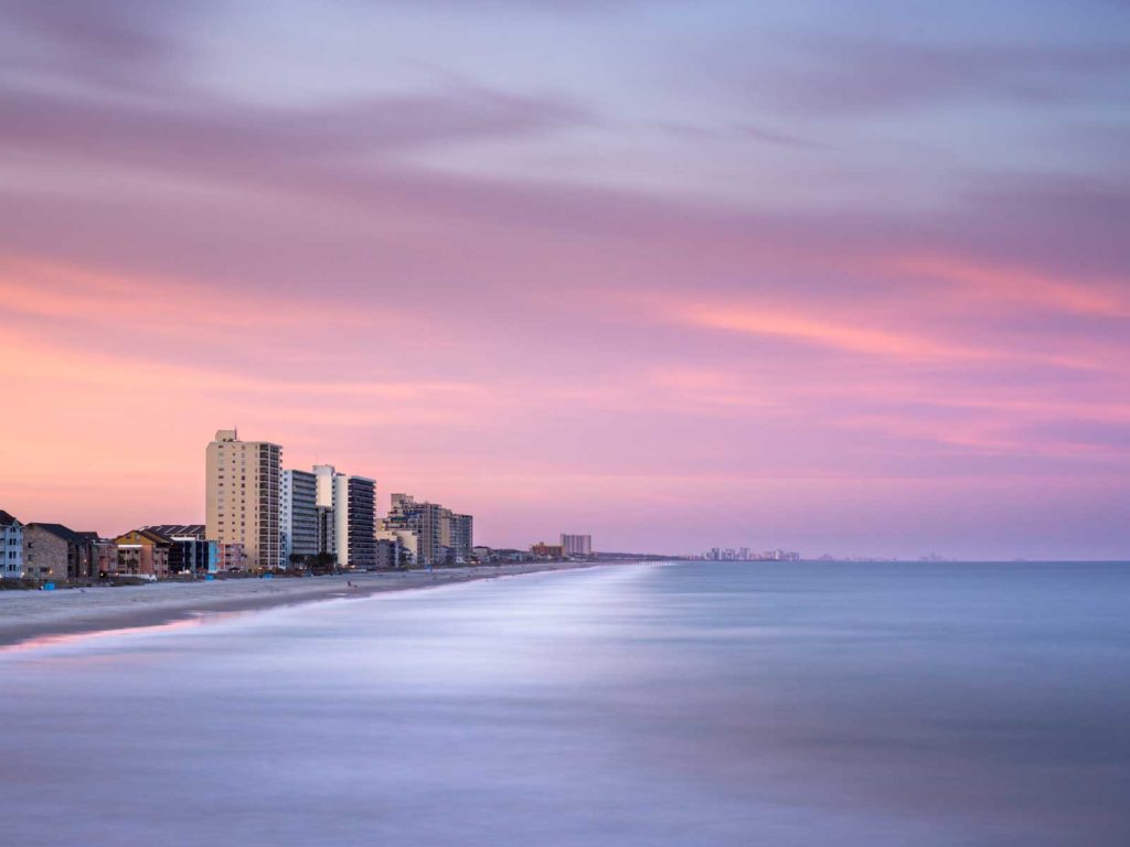 art print of the Garden City shore line in South Carolina, showing a line of highrises with deep sunset colors in the background