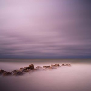 rocky groin with deep purple after sunset colors, an abstract view created by a long exposure photography technique