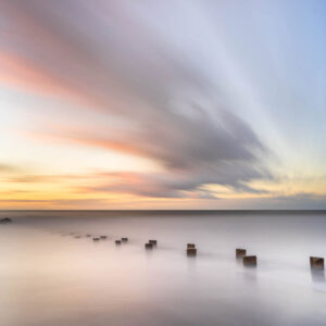 weathered groin on folly beach, South Carolina at sunrise, colorful cloud movement in the background,, art photography